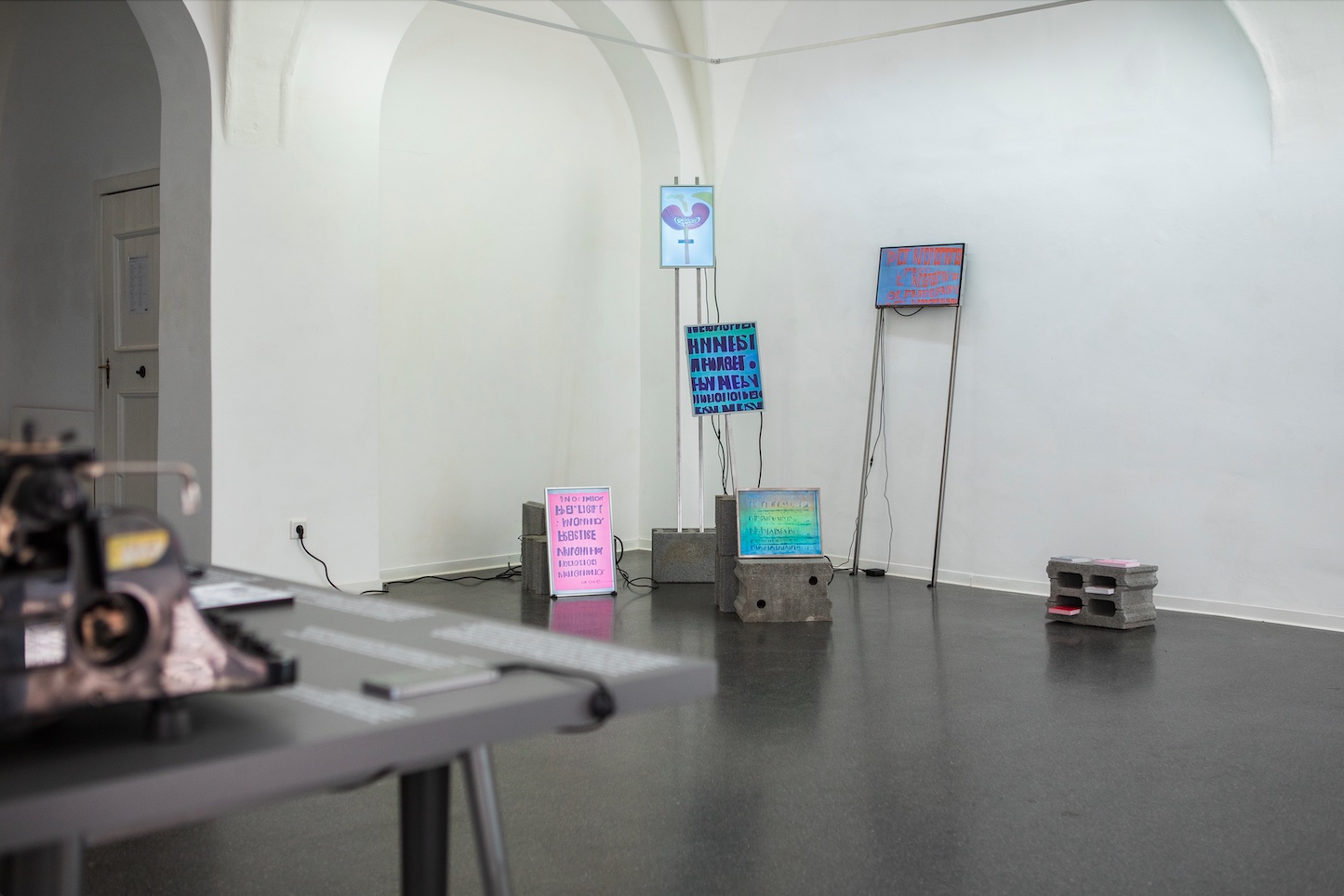 Art exhibition with screens on sticks showing illegible text resembling protest signs